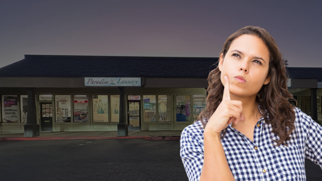 Woman standing outside a laundromat looking thoughtful about remembering to pick up her laundry